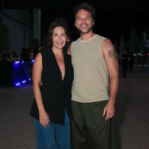 Fabíula Nascimento apostou em uma alfaiataria descontraída com um colete preto decotado sem mangas, jeans wide leg e tênis claros. Ao seu lado, Emílio Dantas combinou uma regata regata listrada em tom bege com calça oversized verde-militar e tênis All Star vermelho de cano baixo. O casal exibiu um visual urbano, moderno e cheio de personalidade