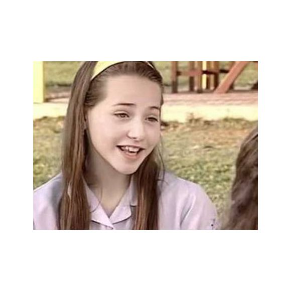 Letícia Colin aparece ainda jovem com cabelo longo e castanho, usado em uma base reta e com poucos elementos de camadas. O visual mantém os fios compridos e naturais, com uma discreta moldura ao redor do rosto