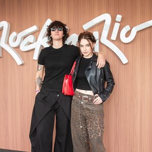 Bel Moreira e Halana Lacerda harmonizam visuais com inspiração indie e elementos do estilo western. Bel destaca uma calça de sarja em estampa de leopardo com cinto de fivela prateada e correntes, jaqueta de couro e bolsa vermelha; Halana aposta no all black com calça de transpasse assimétrico e botas de couro