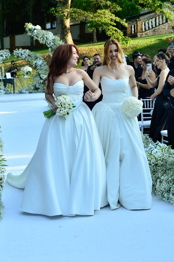 Mari Fernandez e Júlia Ribeiro subiram ao altar com vestidos brancos, em looks clássicos e românticos
