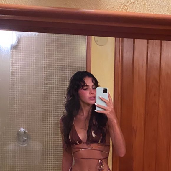 Bruna Marquezine posou no espelho durante uma viagem exibindo a barriga trincada em um biquíni super diferente, em tons terrosos com amarração na cintura.