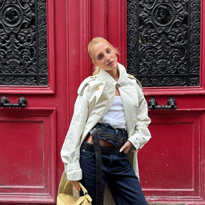 Malu Borges no desfile da Loewe na Paris Fashion Week 25: famosa usa trench coat longo, regata branca, calça jeans e sapatos vermelhos diferentes.
