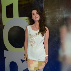 Nathalia Dill apostou em uma estética lúdica e estruturada, utilizando um vestido curto de corte reto na cor off-white, sem mangas e com decote canoa. O destaque da peça frontal é um bordado vertical de paetês em tons pastéis de rosa, amarelo e verde. Na barra, o vestido ganha uma padronagem geométrica em blocos de cores que remetem ao 'pixel art' em tons de pêssego e oliva