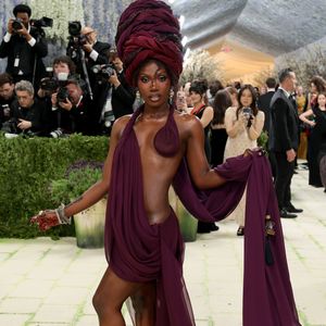 Doechii: a rapper optou por uma abordagem visceral e minimalista, utilizando um drapeado em tom de vinho profundo que mal cobria o corpo, evocando uma estética de deusa antiga. O visual foi complementado por um turbante monumental coordenado, joias de esmeralda e detalhes em henna nas mãos e pés, além de um acabamento de pele ultra-iluminado que ressaltava a dramaticidade da composição