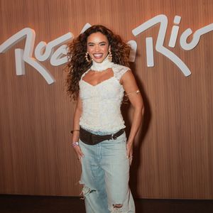 Giovana Cordeiro investe em uma proposta boho chic com toque urbano. A atriz equilibra a delicadeza de um top justo rendado em tom off-white com gola alta e recortes no decote à descomplicação de uma calça jeans wide leg de lavagem clara com rasgos nos joelhos, arrematando com cinto/pochete de couro marrom e grandes argolas douradas