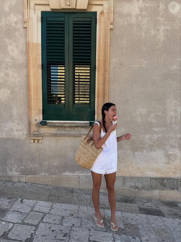 Bruna Marquezine combina macaquinho branco com detalhes em renda com bolsa grande de palha e par de Havaianas