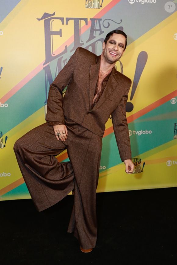 Rainer apareceu com os olhos esfumados em preto, numa maquiagem intensa e marcante que remete ao glam rock e ao universo da performance. Um anel vistoso prateado na mão direita e uma corrente dourada discreta no pescoço completaram o visual, sem disputar atenção com a roupa