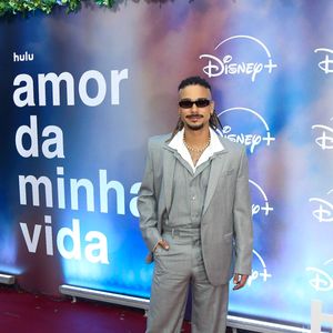 Sérgio Malheiros: opta por um terno cinza-claro de modelagem ampla com colete por baixo e camisa branca de gola aberta, arrematando a produção com colares, óculos escuros e sapatos pretos