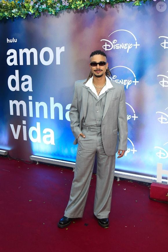 Sérgio Malheiros: opta por um terno cinza-claro de modelagem ampla com colete por baixo e camisa branca de gola aberta, arrematando a produção com colares, óculos escuros e sapatos pretos