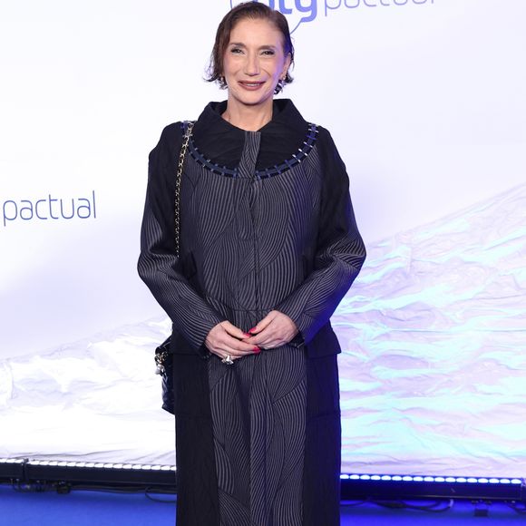 Zizi Possi: Conjunto preto monocromático composto por blusa de gola redonda sob uma jaqueta leve estilo cardigan aberto de mangas longas e calça reta fluida. Como acessórios, usa óculos de grau redondos, brincos discretos e sapatos sociais pretos de bico arredondado