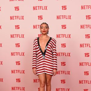 Any Gabrielly: usa um vestido curto de mangas compridas coberto de lantejoulas em riscas horizontais vermelhas e brancas, com um decote profundo em V contornado por orla preta brilhante, finalizado com sapatos scarpin pretos e batom vermelho