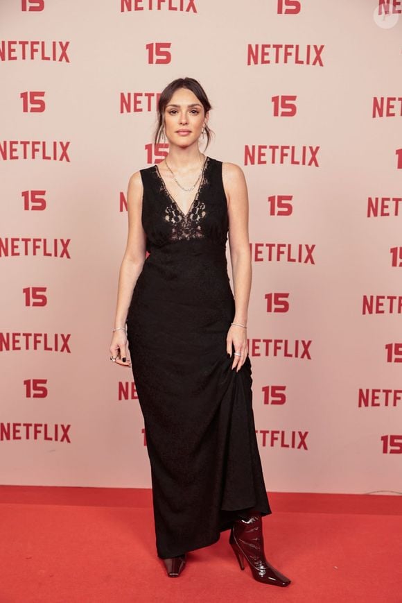 Isabelle Drummond: escolheu um vestido longo preto de estilo camisola (slip dress), apresentando decote em V rendado no busto, complementado por colares delicados, anéis e botas de salto em tom vinil/verniz escuro
