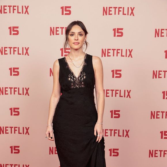 Isabelle Drummond: escolheu um vestido longo preto de estilo camisola (slip dress), apresentando decote em V rendado no busto, complementado por colares delicados, anéis e botas de salto em tom vinil/verniz escuro