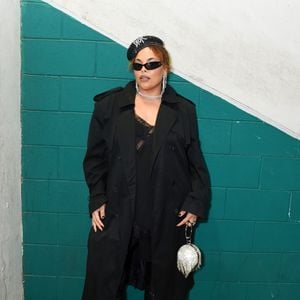 Rita Carreira: exala atitude fashionista ao ostentar um trench coat preto alongado com ombreiras marcadas sobreposto a um vestido estilo slip dress com decote em renda preta. Os acessórios roubam a cena com uma boina cravejada de pedrarias, óculos de sol pretos no estilo cat-eye, brincos e gargantilha brilhantes, botas de couro até o joelho e uma impactante bolsa esférica prateada com franjas reluzentes