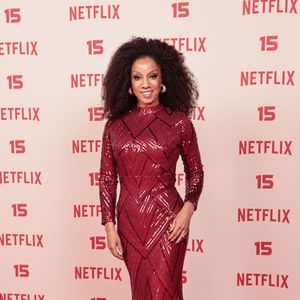 Adriana Lessa: veste um vestido longo justo em tom vermelho-escuro/bordeaux inteiramente coberto de lantejoulas brilhantes, com gola alta e mangas compridas