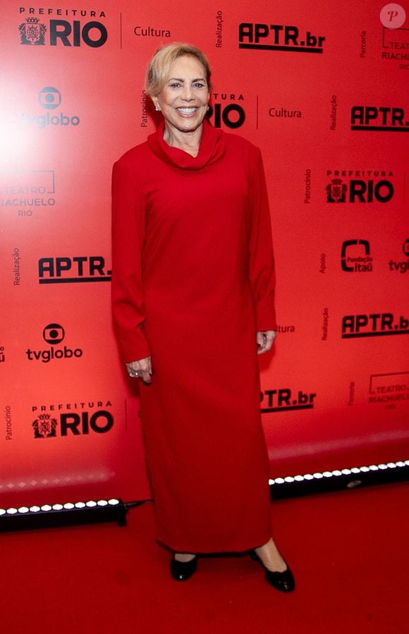 Arlete Salles: A veterana atriz esbanja elegância em um vestido longo inteiramente vermelho de silhueta reta e mangas compridas, caracterizado por uma gola boba volumosa e discreta. Ela complementa o visual minimalista com sapatos pretos de salto baixo e joias delicadas