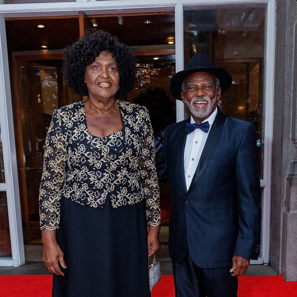 Antônio Pitanga, um dos homenageados da noite, apostou em um terno clássico preto, enquanto sua esposa, Benedita da Silva surgiu em um conjunto composto por saia longa preta fluida e um blazer estruturado de mangas longas, inteiramente trabalhado em renda guipure com bordados dourados sobre fundo escuro