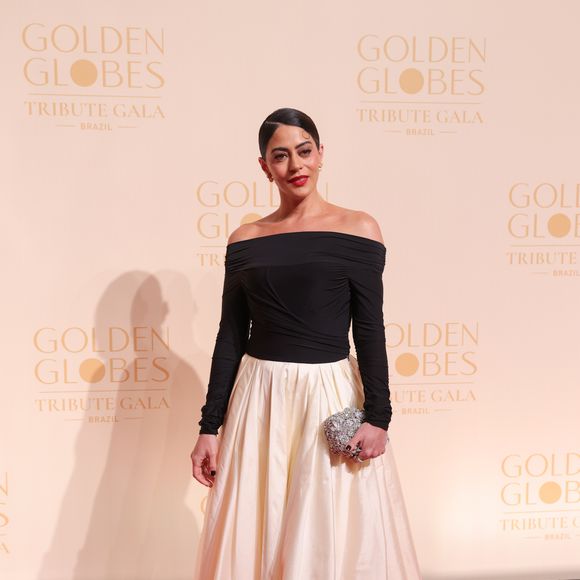 Carol Castro apostou em um visual de elegância clássica com um toque contemporâneo. O ponto focal do look é a saia volumosa em tafetá off-white, com modelagem evasê e comprimento midi, que confere um ar de Old Hollywood à produção