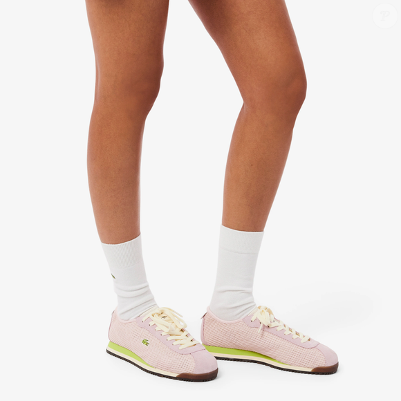 O visual romântico do novo tênis da Lacoste permite combinações com saias plissadas, vestidos, shorts de alfaiataria, jeans claros e peças neutras, reforçando a versatilidade da tendência tenniscore