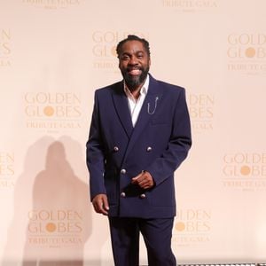 Um dos anfitriões da noite, Lázaro Ramos reafirmou seu estilo sofisticado com um terno trespassado (double-breasted) em tom azul-marinho profundo. A modelagem do blazer é ligeiramente oversized, conferindo modernidade à alfaiataria tradicional, destacada pelos botões metálicos prateados em alto relevo. Um detalhe de mestre é o broche de corrente delicado na lapela esquerda, que adiciona um ponto de brilho discreto, harmonizando com os mocassins pretos de couro polido