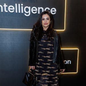 Renata Bráz comparece ao evento com uma combinação de texturas e estampas marcantes. Ela exibe um vestido longo de base escura e tecido fluido, inteiramente decorado com uma padronagem repetida de leopardos em tons dourados e beges. A barra do vestido revela uma leve transparência sob a luz. Para se proteger do frio, Liége sobrepõe a peça com um casaco preto confeccionado em material que imita pele, apresentando debruns frontais com acabamento em couro sintético liso. Como acessórios, ela carrega uma bolsa de mão estruturada em couro preto brilhante e calça botas de bico fino na mesma cor