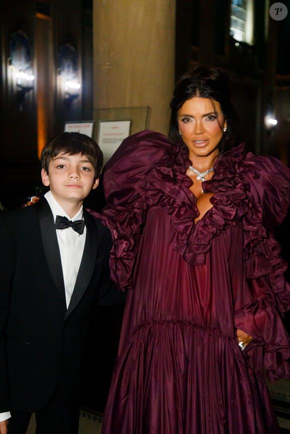 Mãe da noiva, Cynthia Marques escolheu um vestido vinho com bastante volume nos ombros e babados em camadas