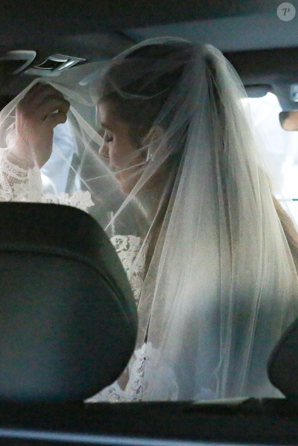 A cantora Giulia Be foi fotografada dentro do carro antes de seu casamento com Conor Kennedy. O look escolhido para a cerimônia reúne renda floral, gola alta e véu sobre o rosto