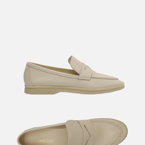 Com salto rasteiro, base bege e bico redondo, o modelo fechado traz recorte lateral na gáspea e aplicação de tira de couro vazada sobre o cabedal