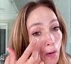 Jennifer Lopez aplica um produto, que parece ser creme ou sérum, na área dos olhos, provavelmente, para suavizar olheiras