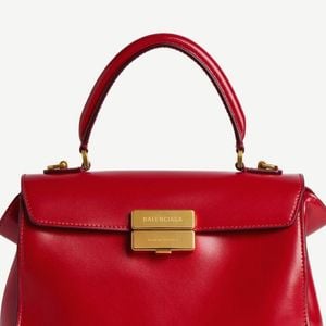 O look de Virginia foi complementado por bolsa de mão estruturada vermelha com fecho dourado e sapatos vermelhos de salto alto