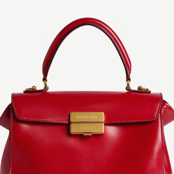 O look de Virginia foi complementado por bolsa de mão estruturada vermelha com fecho dourado e sapatos vermelhos de salto alto