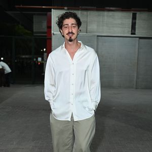 Jhonny Massaro apostou na elegância despretensiosa com uma camisa de seda fluida branca com os botões superiores abertos, criando um decote V suave. O ator combinou a peça com uma calça chino bege de caimento reto e folgado e sapatos sociais pretos de solado grosso. A produção destacou seu estilo autoral, minimalista e sofisticado