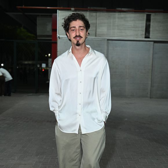 Jhonny Massaro apostou na elegância despretensiosa com uma camisa de seda fluida branca com os botões superiores abertos, criando um decote V suave. O ator combinou a peça com uma calça chino bege de caimento reto e folgado e sapatos sociais pretos de solado grosso. A produção destacou seu estilo autoral, minimalista e sofisticado