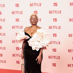 Shirley Cruz: veste um modelo longo de veludo preto com corte sereia e decote sem alças, destacado por duas volumosas flores estruturadas em tom rosa-quartzo na região do busto e ombros