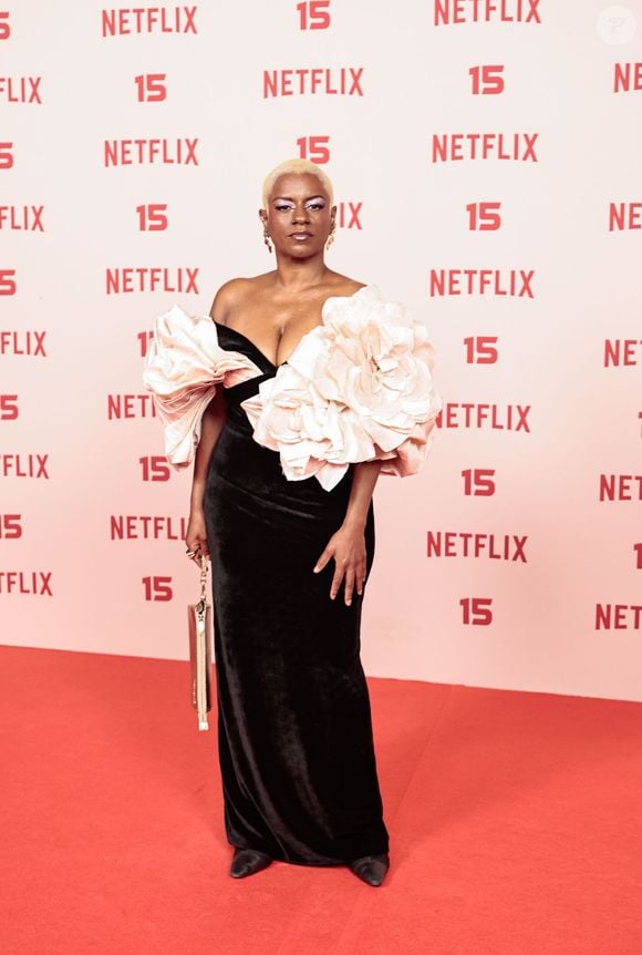 Shirley Cruz: veste um modelo longo de veludo preto com corte sereia e decote sem alças, destacado por duas volumosas flores estruturadas em tom rosa-quartzo na região do busto e ombros