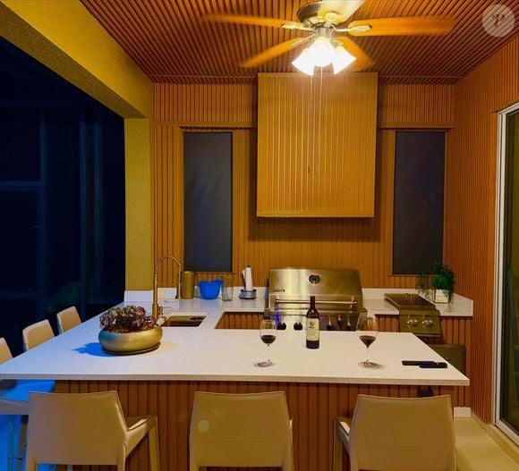 A área gourmet da mansão de Rick Sollo, da dupla sertaneja Rick e Renner, tem churrasqueira e detalhes de madeira ripada. O ambiente faz parte da área externa da propriedade de luxo adquirida pelo cantor e a esposa na Flórida