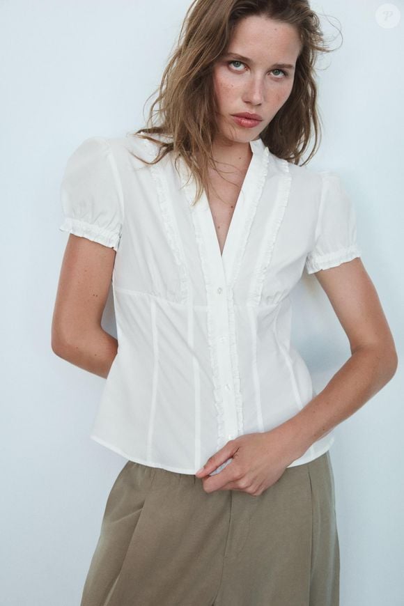 A Camisa de Popelina com Abertura e Laços da Zara tem modelagem ajustada, gola redonda, manga curta e detalhes de abertura e laços na parte frontal