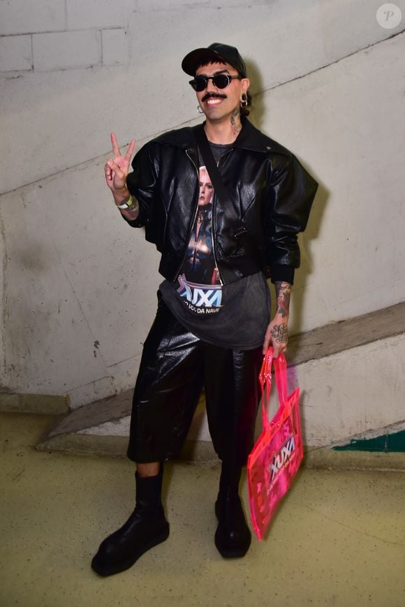 Edu apostou em uma produção streetwear conceitual composta por jaqueta de couro preta e bermuda ampla de mesmo material. Por baixo, vestiu camiseta vintage com estampa temática do show "Xuxa - O Último Voo da Nave", somada a óculos escuros e boné