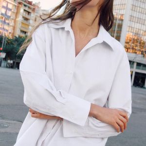 Em branco, a Camisa Básica Oxford da Zara tem fechamento frontal por botões e mangas amplas com acabamento em punho, além de gola de lapela e decote V