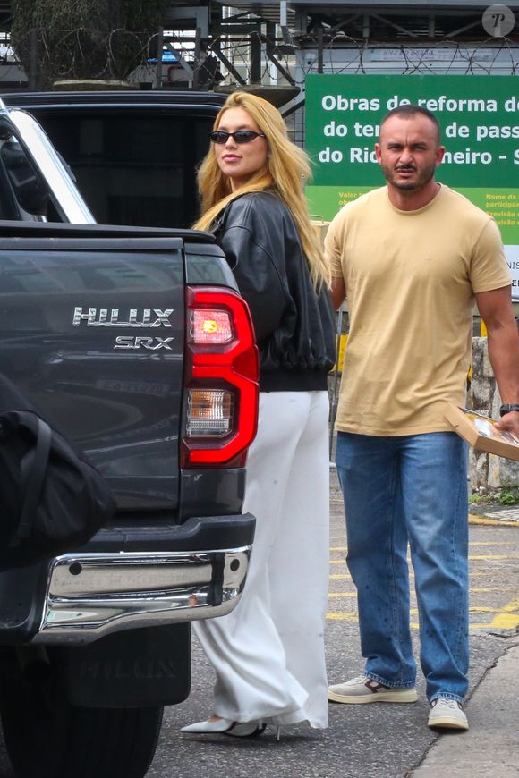 Nos pés, a escolha foi um scarpin branco de bico fino e salto alto, reforçando a elegância do visual e harmonizando com a calça clara.