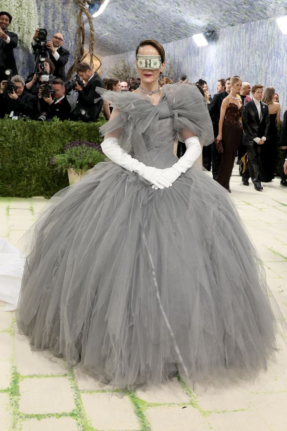 Sarah Paulson cruzou o tapete vermelho com um volumoso vestido de tule cinza e luvas brancas clássicas, surpreendendo a todos ao utilizar uma nota de dólar dobrada como uma máscara improvisada sobre os olhos