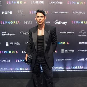 Theodoro apostou no clássico 'all black' com um toque de brilho noturno e sofisticação. O influenciador veste um blazer de lapela acetinada sobre uma regata preta básica, deixando o foco total para a calça de modelagem ampla inteiramente recoberta por microcristais que refletem a luz de forma sutil. O visual é arrematado por botas de bico fino e uma clutch estruturada preta, mantendo uma elegância moderna e urbana