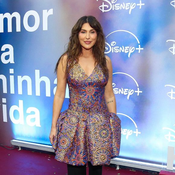 Fernanda Paes Leme: investe na sobreposição de um vestido estruturado multicolorido com padronagem brocada e volume no quadril sobre uma calça preta reta, arrematando com sapatos verdes de bico quadrado