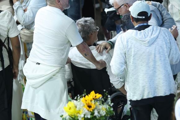 De costas, Carlinhos de Jesus apareceu sendo carregado por um homem na cadeira de rodas