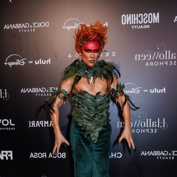 Theodoro, com inspiração no Curupira, veste um conjunto composto por calça de veludo verde-escuro e um top estruturado feito por folhagens esculpidas sobre o peitoral. O visual é complementado por uma gola com folhagens e dentes/garras decorativas, braçadeiras com tiras e folhagens, unhas compridas pretas, maquiagem facial vermelha ao redor dos olhos e cabelo eriçado em tom avermelhado