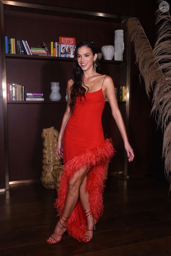 Moda de Bruna Marquezine para épocas de festas, como esse vestido com uma fenda poderosa, aliado aos acessórios também na cor vermelha, é uma ótima pedida para o seu look de Natal.