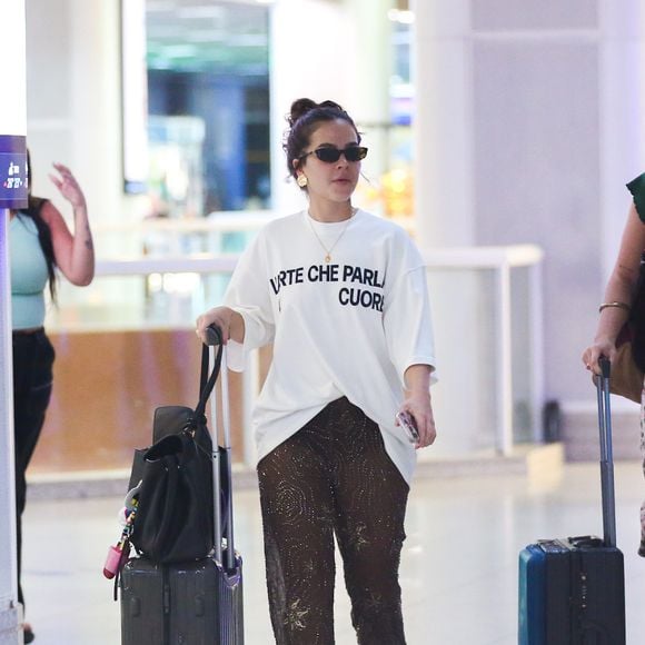 Mel Maia circulou de óculos escuros e um look comfy, composto de camisão branco e uma calça preta transparente com brilhos discretos