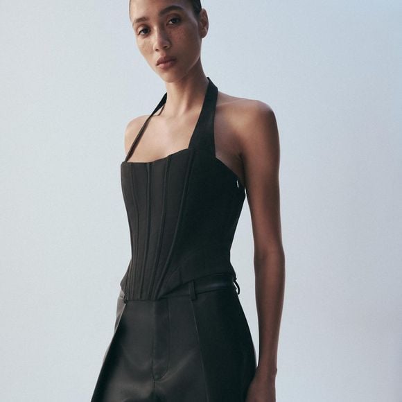O top de inspiração corset com gola halter da Zara tem decote reto, laços nas costas e barra assimétrica, detalhes que valorizam a região dos ombros e da cintura. O modelo custa R$ 279,00