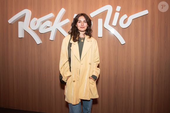 Marina Moschen quebrou a sequência de looks pretos e de couro no Rock in Rio 2026 ao apostar em um trench coat bege, combinado com jeans e blusa cinza de mangas compridas para curtir o festival