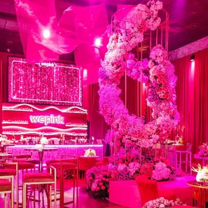 Poltronas rosa-chiclete, mesas douradas e flores formam um dos lounges da festa da WePink